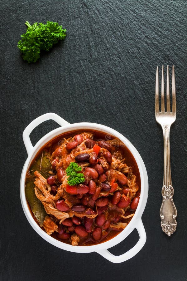 Feijões com a carne de porco cozido no molho de tomate picante com cebola, paprika, cerveja, sino e pimenta cor-de-rosa foto de stock royalty free Feijões com a carne de porco cozido no molho de tomate picante com cebola, paprika, cerveja, sino e pimenta cor-de-rosa foto de stock royalty free