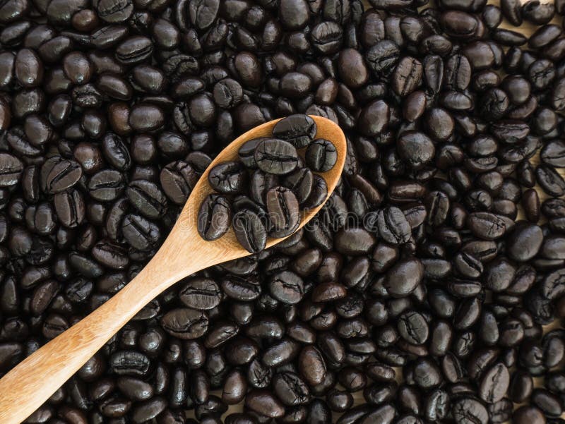 Top view of black coffee beans in wood spoon on wood background. Top view of black coffee beans in wood spoon on wood background