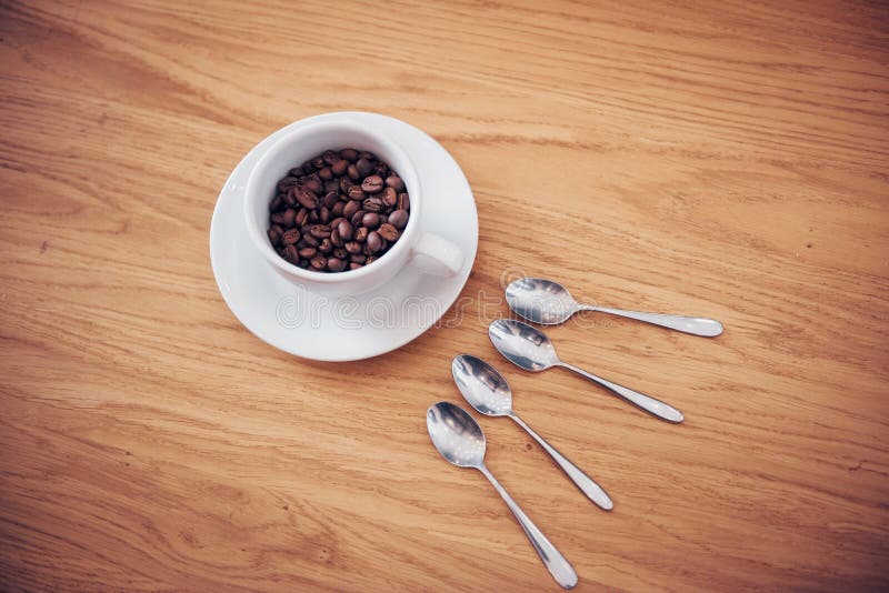 Coffee beans and white cup of coffee and 4 spoons. Coffee beans and white cup of coffee and 4 spoons.