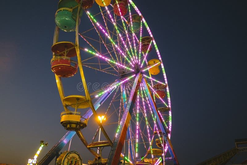 Feira de condado na noite Ferris Wheel no meio do caminho imagem de stock royalty free Feira de condado na noite Ferris Wheel no meio do caminho imagem de stock royalty free