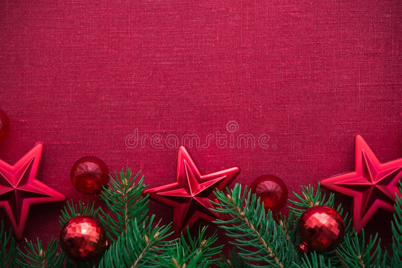 Feld mit Weihnachtsbaum und Verzierungen auf rotem Segeltuchhintergrund Frohe Weihnacht-Karte