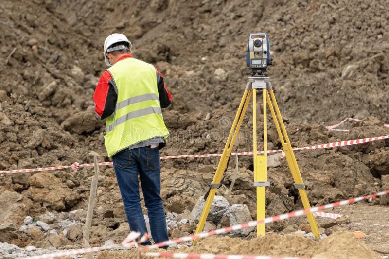 Feldmesser an der Baustelle führt Maße durch lizenzfreies stockfoto Feldmesser an der Baustelle führt Maße durch lizenzfreies stockfoto