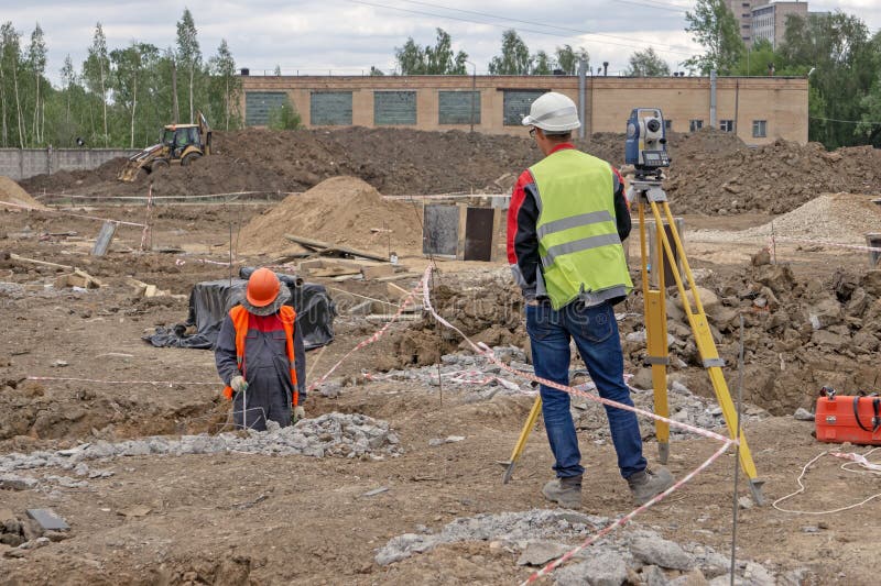 Feldmesser an der Baustelle führt Maße durch lizenzfreies stockfoto Feldmesser an der Baustelle führt Maße durch lizenzfreies stockfoto