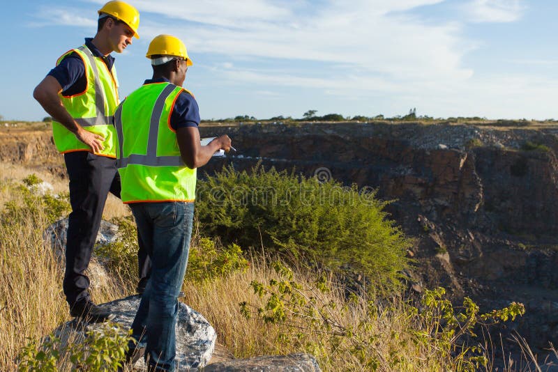 Two male surveyors working at mining site. Two male surveyors working at mining site