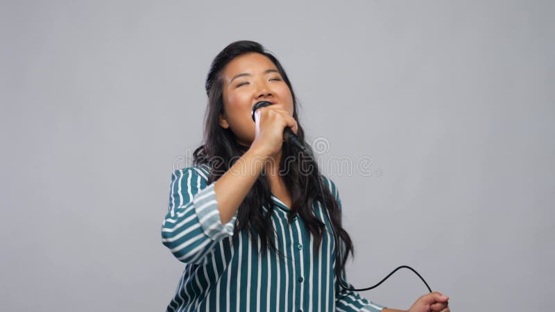 Felice donna asiatica col microfono che canta il karaoke