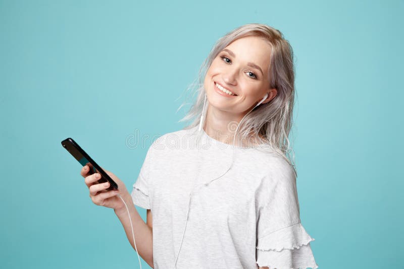Felice donna con cuffie e telefono che ascolta la musica in studio fotografie stock libere da diritti Felice donna con cuffie e telefono che ascolta la musica in studio fotografie stock libere da diritti