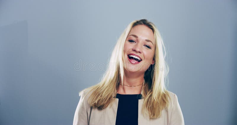 Felice donna faccia a faccia e ride in studio per meme allegro espressione ed emoji sullo sfondo grigio. modello di ritratto