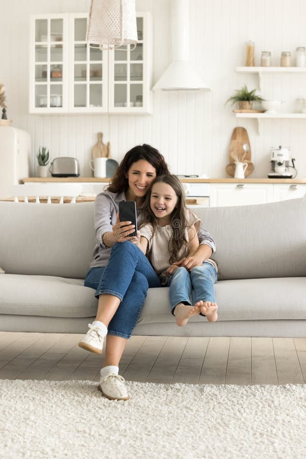 Felice mamma millenaria figlia che gioca al telefono fotografie stock