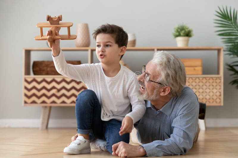 Felice nonno e nipote che giocano con un giocattolo in aereo di legno immagini stock libere da diritti
