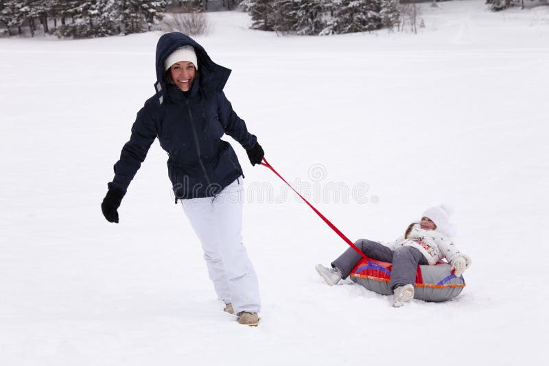 ` Felice s della madre che prova a alzarsi la figlia della collina che si siede nello sno fotografie stock libere da diritti ` Felice s della madre che prova a alzarsi la figlia della collina che si siede nello sno fotografie stock libere da diritti