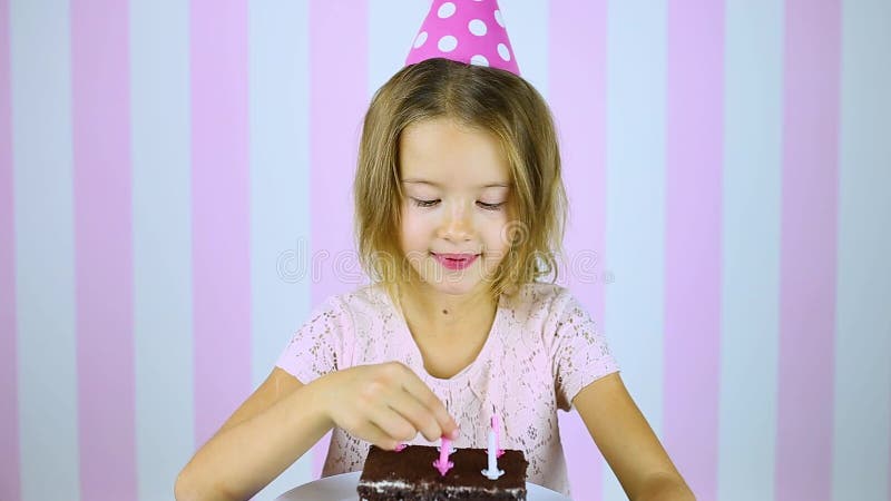 Felice sorpresa occhi chiusi piccola ragazza con berretto rosa che spegne candele