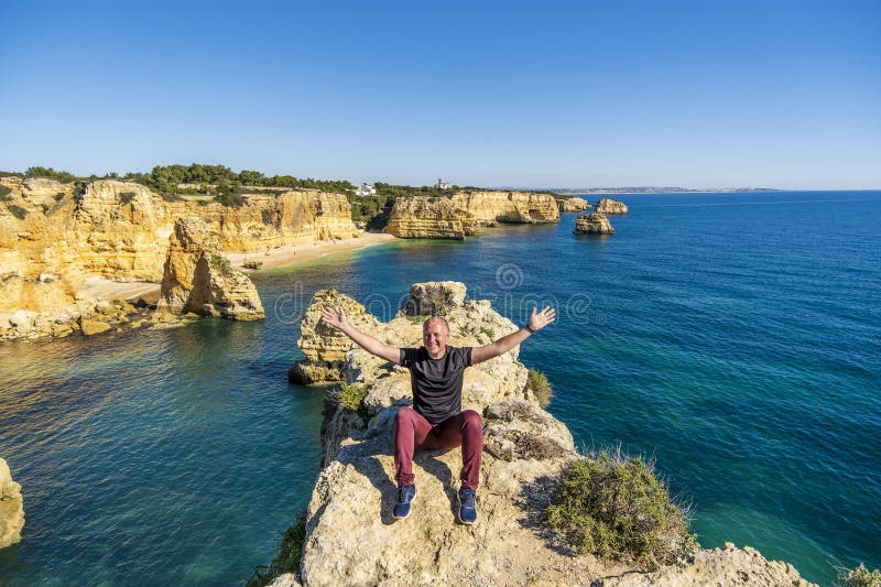 Felice uomo seduto sulla cima delle scogliere a marinha Beach algarve portugal fotografie stock libere da diritti
