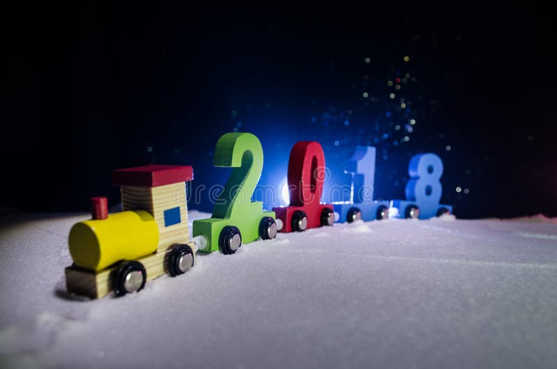 2018 happy new year,wooden toy train carrying numbers of 2018 year on snow. Toy train with 2018. Copy space. Christmas decoration. Selective focus. Dark background. 2018 happy new year,wooden toy train carrying numbers of 2018 year on snow. Toy train with 2018. Copy space. Christmas decoration. Selective focus. Dark background