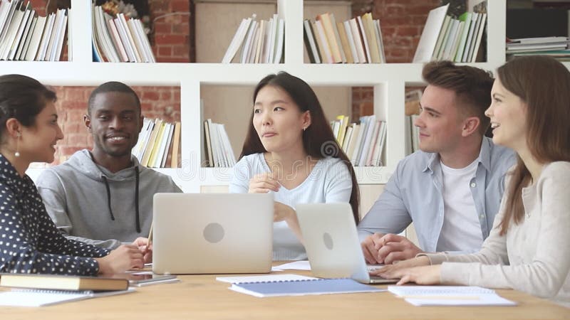 Felices estudiantes diversos escuchando a un compañero de grupo de las Coreas Asiáticas