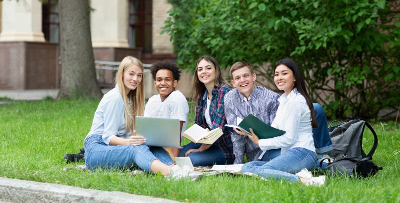 Felices estudiantes universitarios descansando en el campus, sonriendo a la cámara