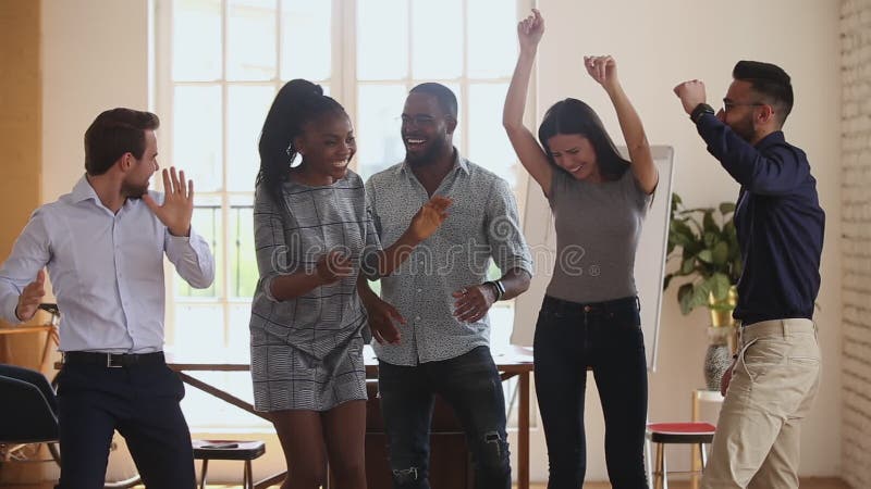 Felices y diversos empresarios bailando en la oficina, celebrando los logros corporativos