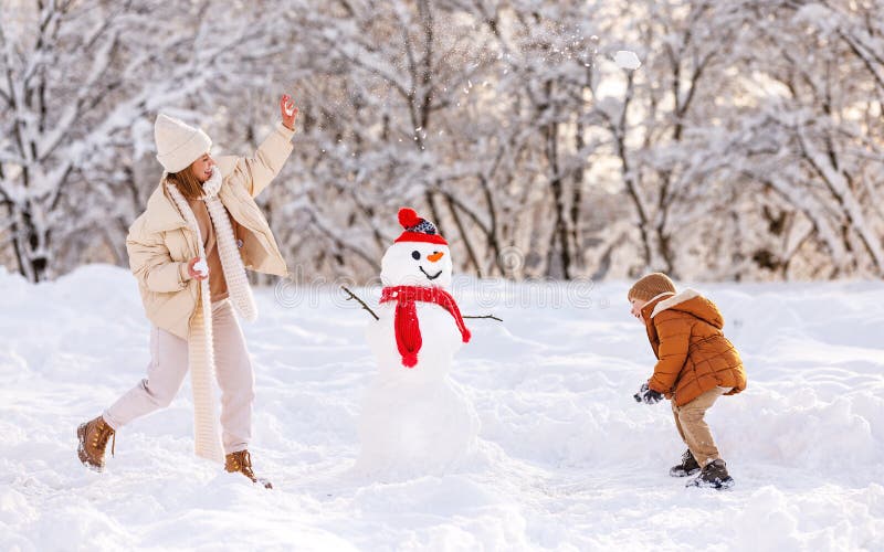 Felici di avere una famiglia madre e un figlio giocano a palle di neve all'aperto in inverno