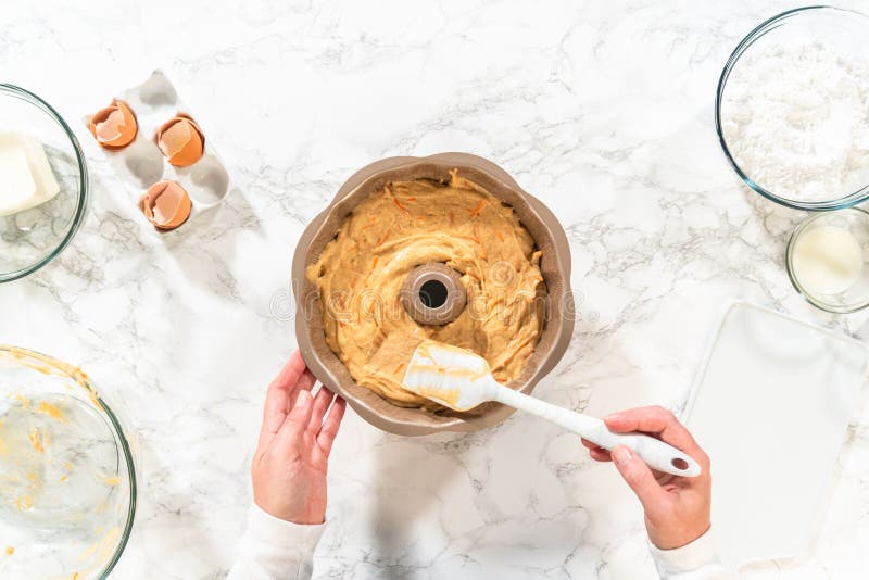 The greased bundt cake pan is filled with cake batter, ready to be baked into a delectable Carrot Bundt Cake. The greased bundt cake pan is filled with cake batter, ready to be baked into a delectable Carrot Bundt Cake.