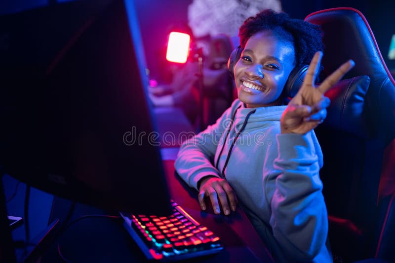 Felicità della giovane donna africana cyber-videogamer professionista videogame online computer color scuro immagini stock libere da diritti