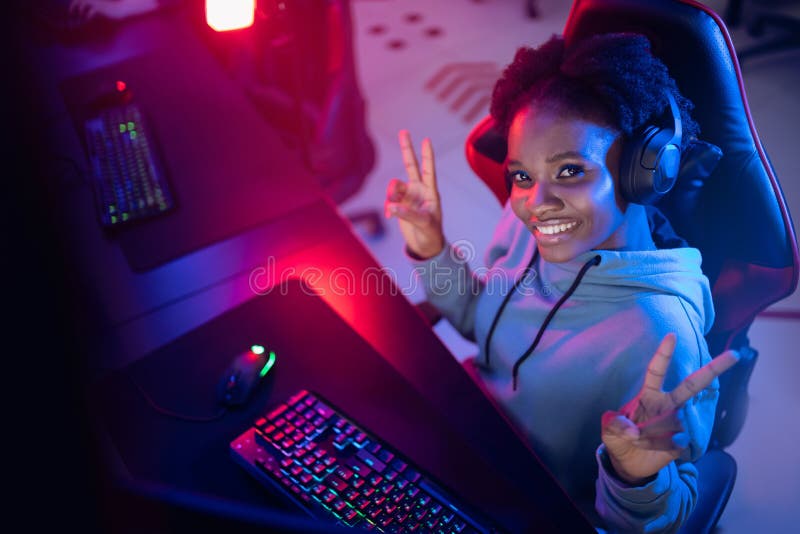 Felicità della giovane donna africana cyber-videogamer professionista videogame online computer color scuro fotografie stock libere da diritti