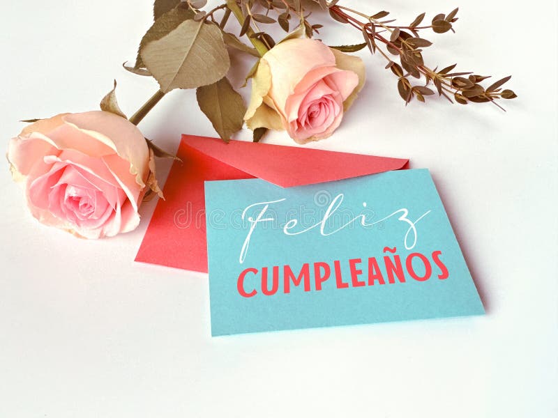 A card with the words Felis Cumpleanos written on it, or Happy Birthday in Spanish, is placed next to a bouquet of red gerbera flowers. A card with the words Felis Cumpleanos written on it, or Happy Birthday in Spanish, is placed next to a bouquet of red gerbera flowers.