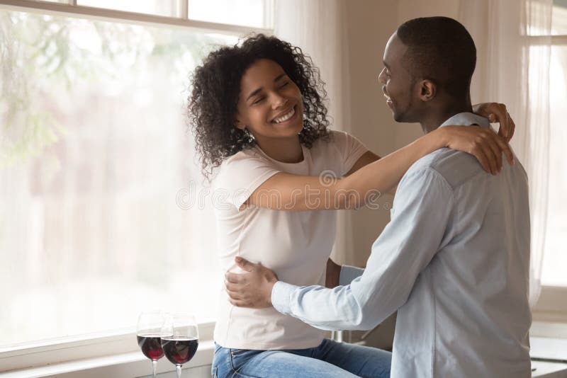 Feliz abrazo de pareja birracial disfrutando de una cita romántica en casa