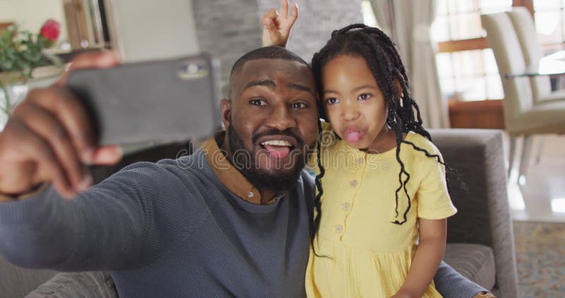 Feliz afro-americana filha e pai tomando selfie no sofá