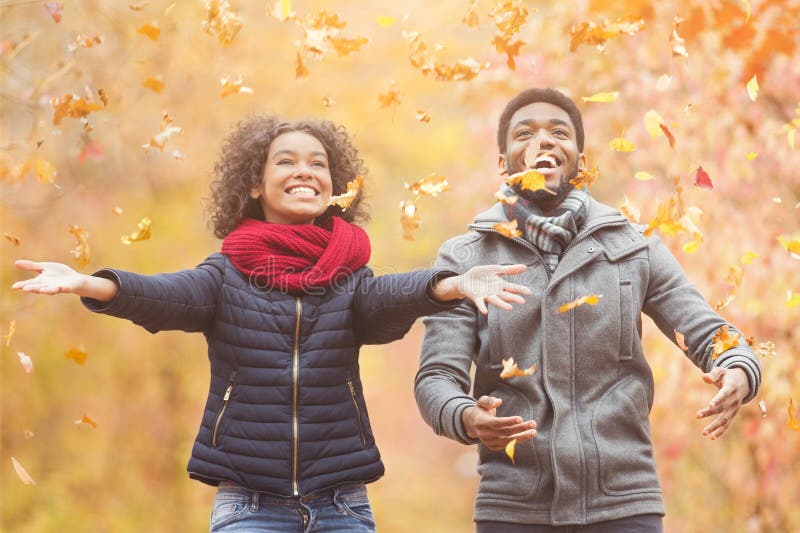 Feliz afro pareja lanzando hojas de otoño imágenes de archivo libres de regalías Feliz afro pareja lanzando hojas de otoño imágenes de archivo libres de regalías