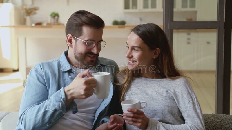 Feliz amando a las esposas casadas relajándose en el sofá tomando té caliente.