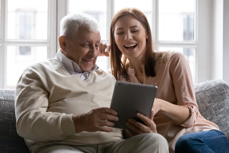 Feliz anciano y hija mayor usando una tableta juntos fotos de archivo libres de regalías