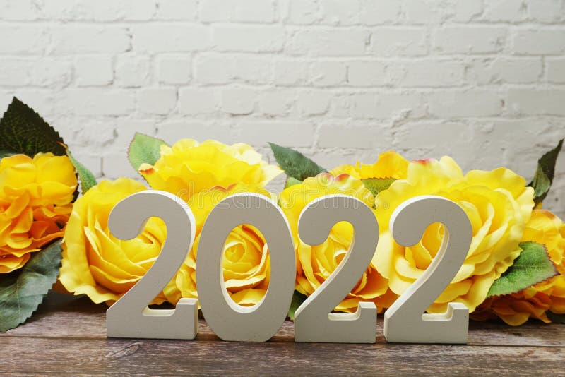 Happy New Year 2022 with Roses Flower Decoration with space copy on white brick wall. Happy New Year 2022 with Roses Flower Decoration with space copy on white brick wall