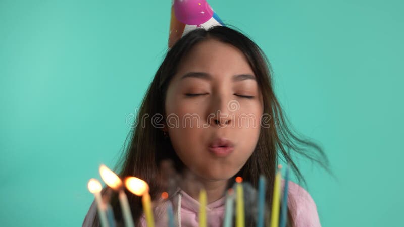 Feliz asiática soprando velas no aniversário