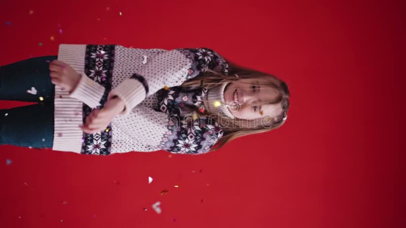 Feliz chica con suéter lanza confetti con fondo rojo almacen de video