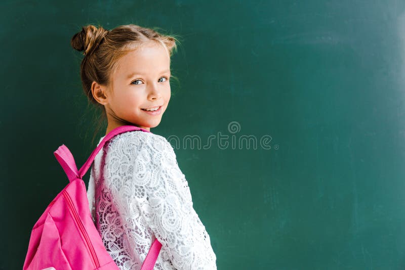 happy schoolkid smiling while standing with backpack on green ,stock image. happy schoolkid smiling while standing with backpack on green ,stock image