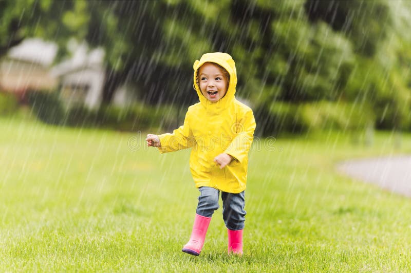 Feliz criança engraçada com capa de chuva sob o dia de chuva de verão imagens de stock royalty free