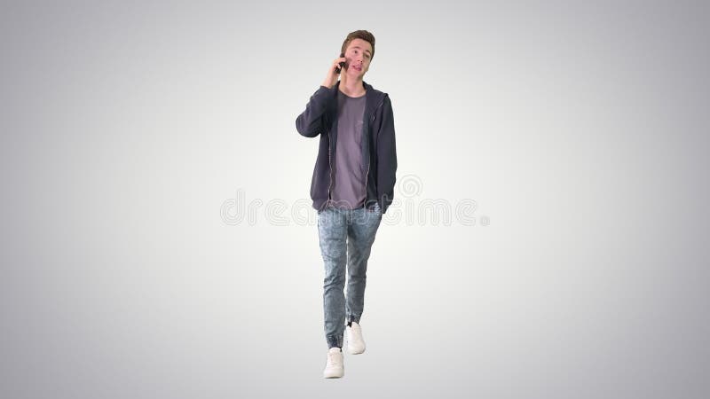 Feliz estudiante caminando y hablando por celular sobre fondo gradiente. metrajes