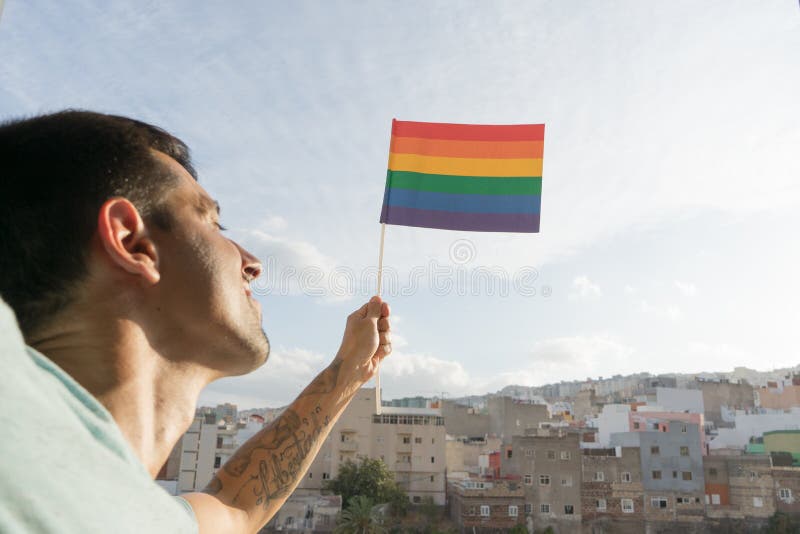 Feliz homossexual levantou a bandeira do arco-íris para a sociedade pela liberdade civil e apoiou a liberdade e identidade sexuai imagem de stock Feliz homossexual levantou a bandeira do arco-íris para a sociedade pela liberdade civil e apoiou a liberdade e identidade sexuai imagem de stock