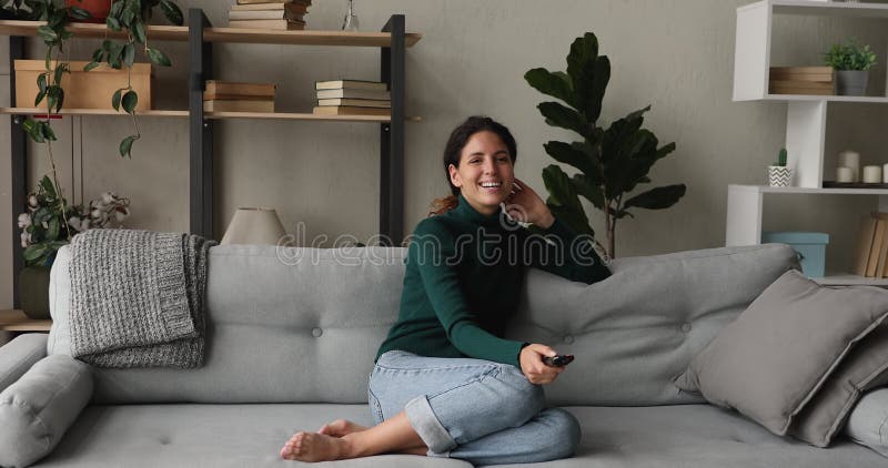 Feliz joven relajada viendo la tele en casa.