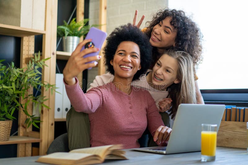 Feliz madre afroamericana y sus hijas adolescentes usando aplicaciones de smartphones para comprar en los medios sociales fotos de archivo libres de regalías