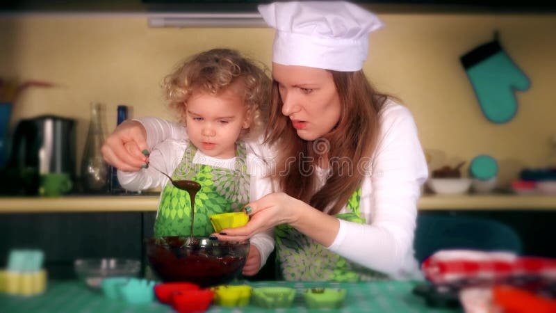 Feliz madre e hija preparando pastelitos en la cocina. clasificación de color dramática