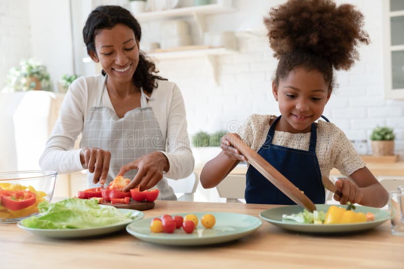 Feliz madre y niño compartiendo tareas de cocina preparando ensalada