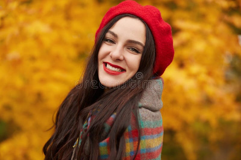 Feliz morena en Autumn Park, jovencita divirtiéndose afuera rodeada de árboles y hojas amarillas, mujer sonriente posando fotos de archivo libres de regalías Feliz morena en Autumn Park, jovencita divirtiéndose afuera rodeada de árboles y hojas amarillas, mujer sonriente posando fotos de archivo libres de regalías