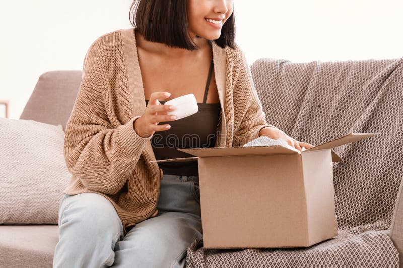 Feliz mujer asiática desempacando paquete con caja de belleza imagen de archivo