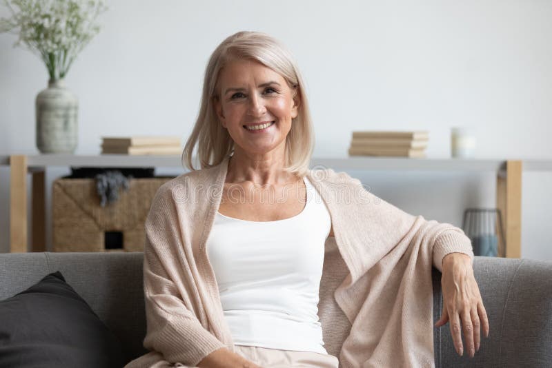 Feliz mujer de mediana edad mirando la cámara en casa foto de archivo