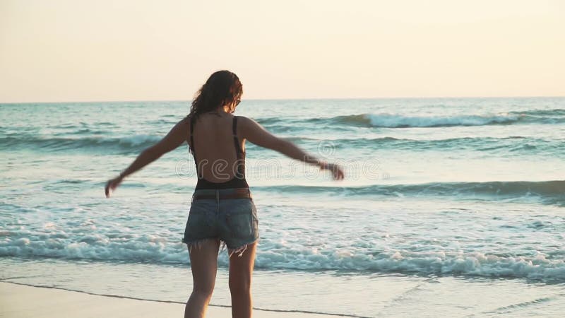 Feliz mujer disfruta de vacaciones en la playa al atardecer