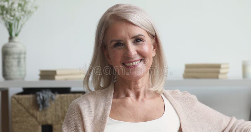 Feliz mujer mayor de mediana edad mirando la cámara en casa