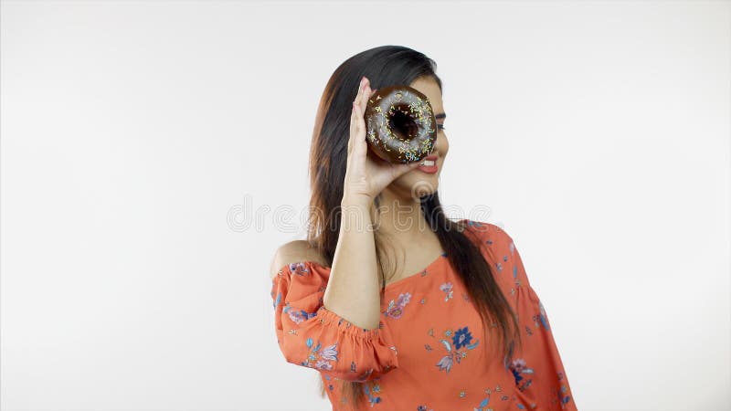 Feliz mulher moderna sorrindo e brincando com donuts em roupas casuais - conceito de lazer