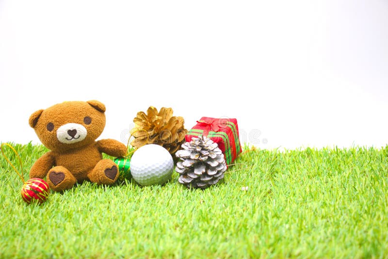 Bear and one golf ball with Christmas ornament on green grass. Bear and one golf ball with Christmas ornament on green grass