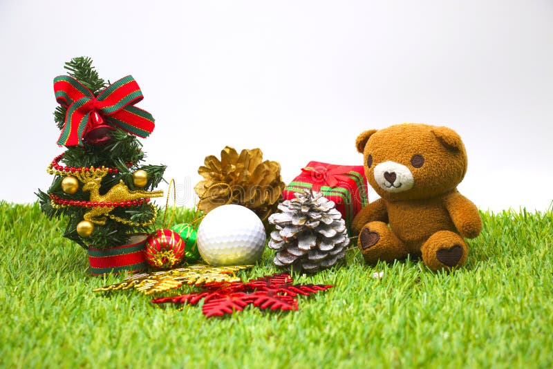 Bear and one golf ball with Christmas ornament on green grass. Bear and one golf ball with Christmas ornament on green grass