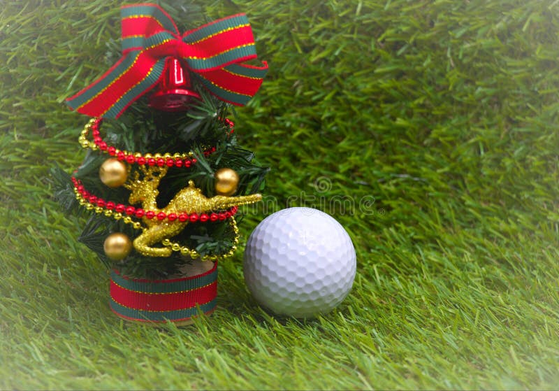 One golf ball with Christmas tree on green grass. One golf ball with Christmas tree on green grass